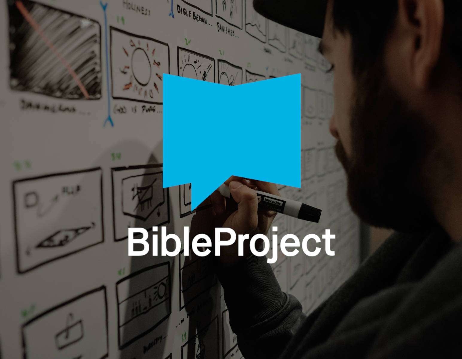 A man in the background sketching with a marker on a chalkboard. In the foreground, the BibleProject logo.