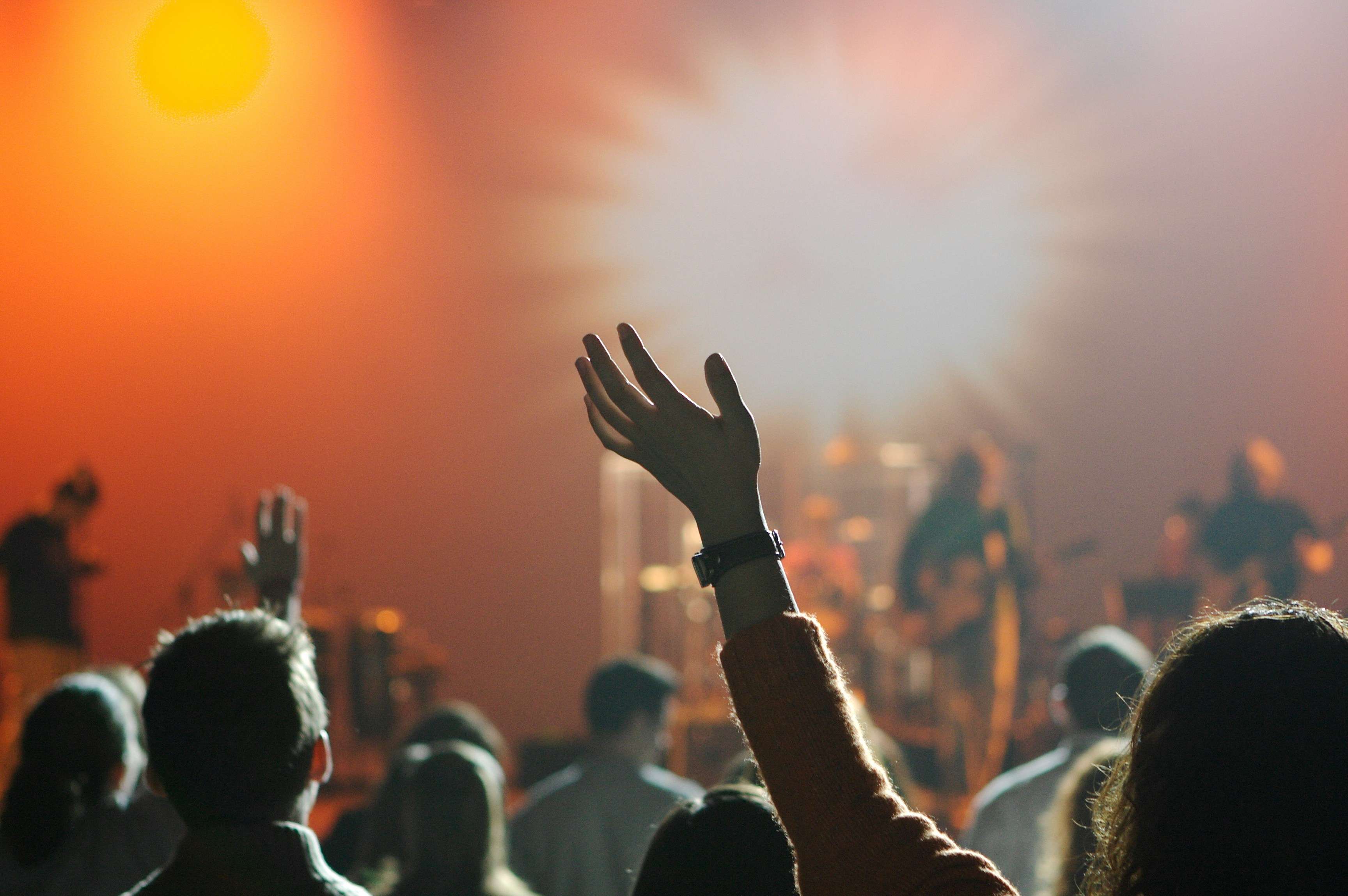 In the foreground, young people worshiping. In the background, a band.