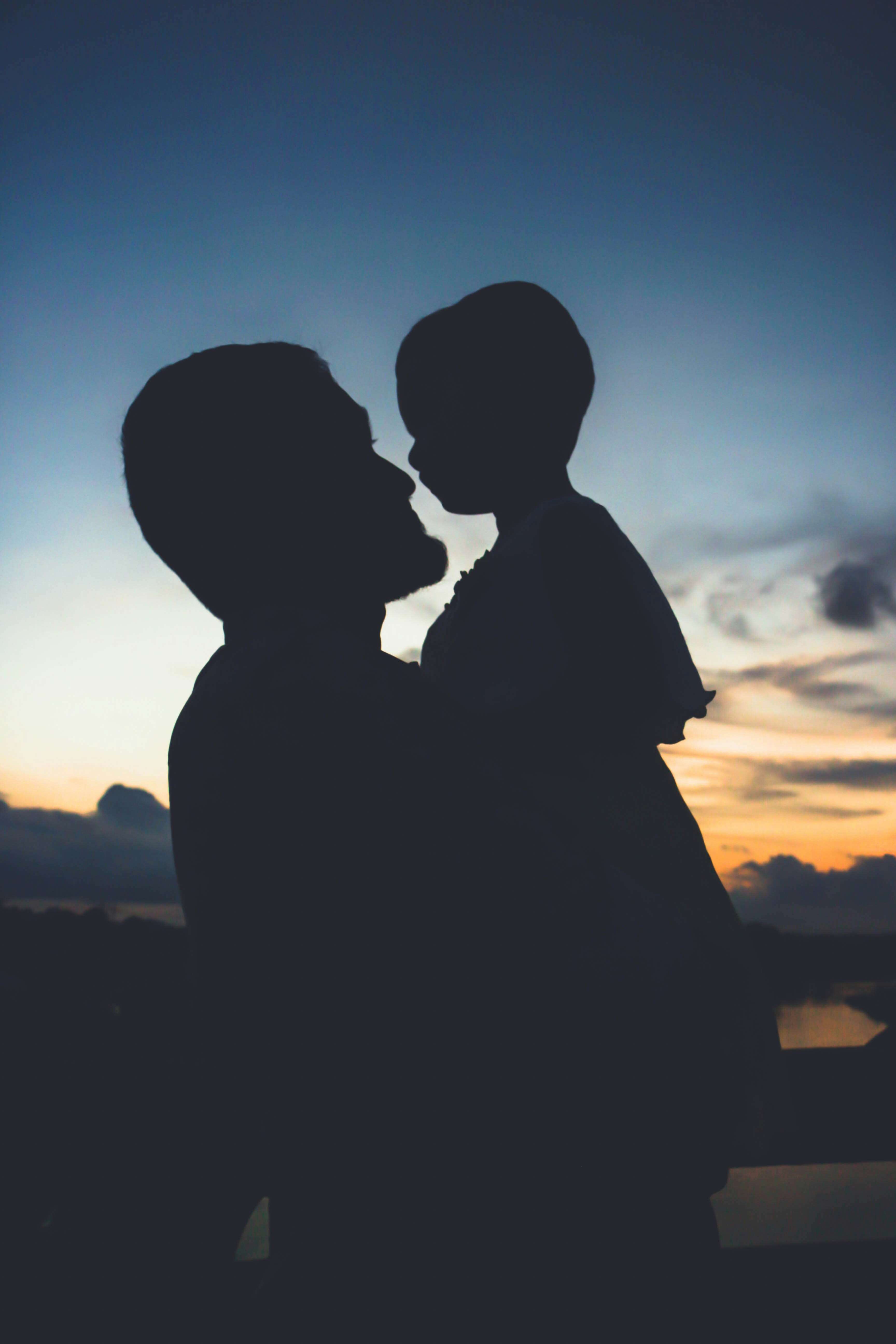 Silhouette of a father holding a child in his arms.